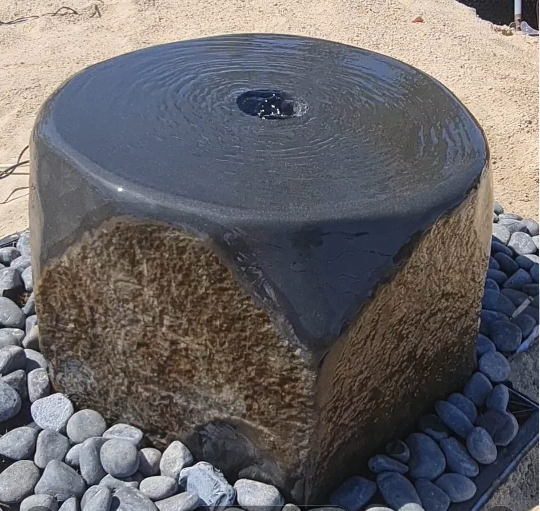 Basalt boulder fountain with water flowing over the crown