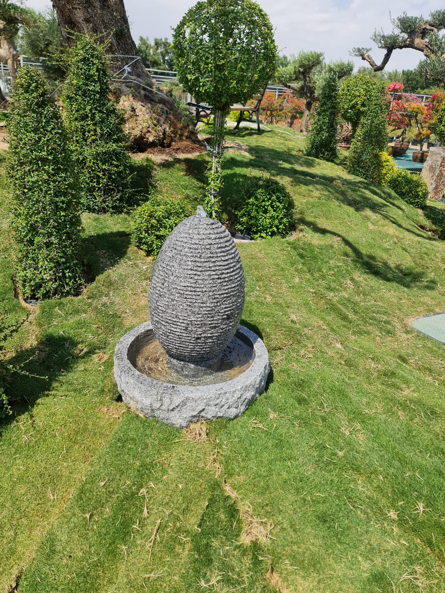 Oval stone fountain with rippling water across its face