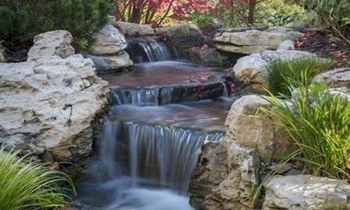 Medium pondless waterfall running through a landscaped bed