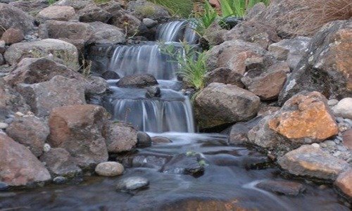 Pondless waterfall spilling over stacked rock into a hidden reservoir