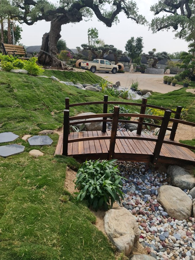 Wooden garden bridge crossing a bed of river pebbles